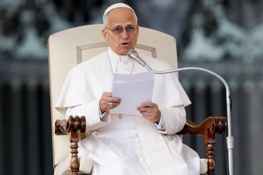 Pave Leo XIV sitter på en stol på Petersplassen og leser fra et ark