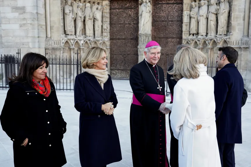 Paris' erkebiskop Laurent Ulrich hilser på Frankrikes førstedame Brigitte Macron utenfor Notre-Dame de Paris.