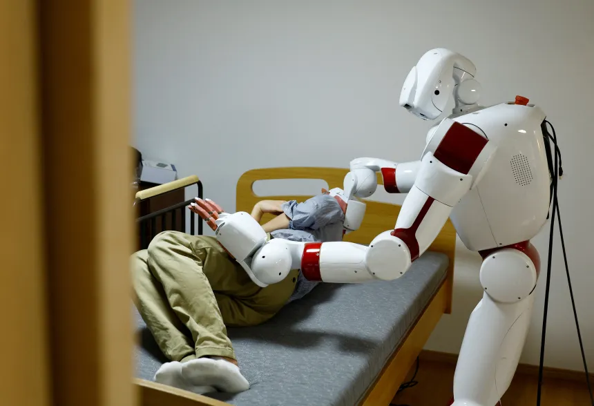 En robot står ved siden av en mann som ligger i en seng