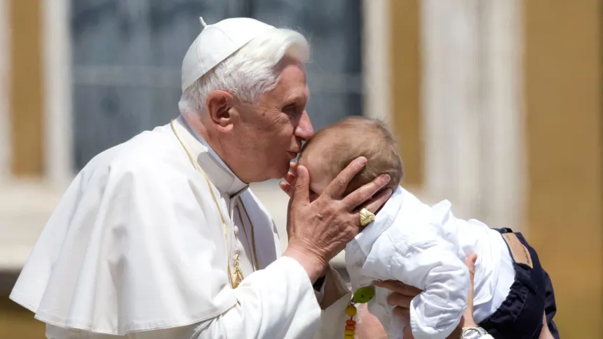 Pave Benedikt XVI kysser et barn på Petersplassen