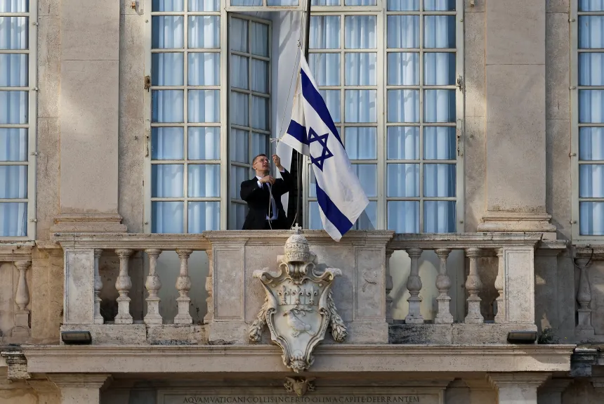 En mann heiser det israelske flagg på en balkong i Vatikanet