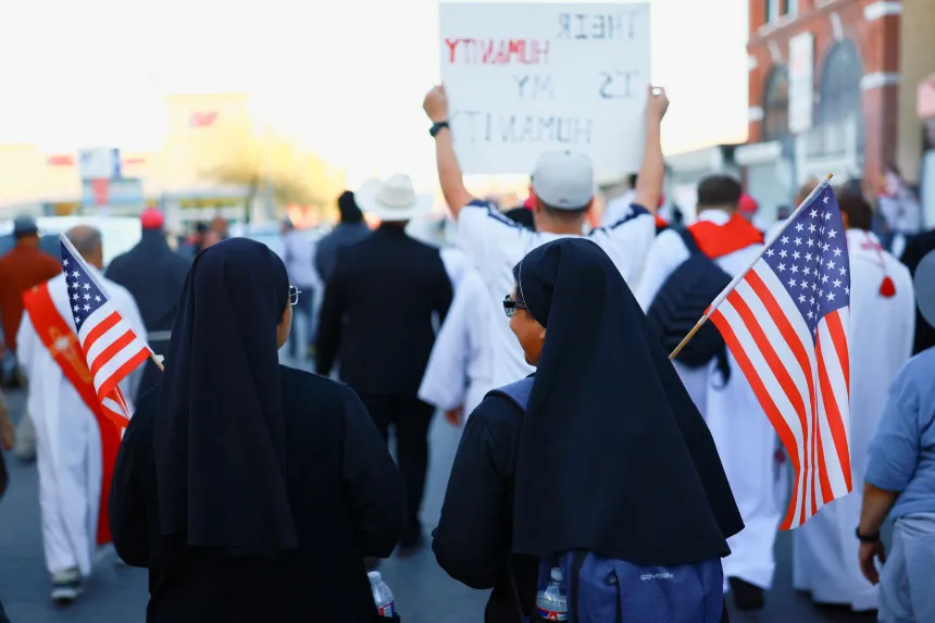 To ordenssøstre med amerikanske flagg deltar i en marsj