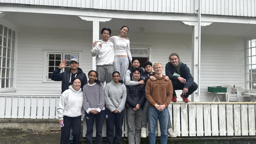 Gruppe med deltakere foran et hvitt hus