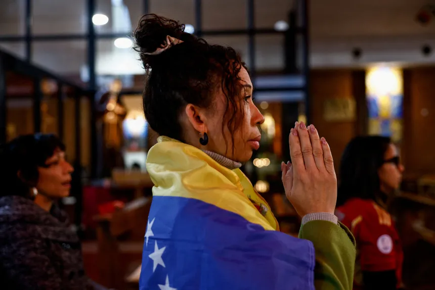 Kvinne kledd i et venezuelansk flagg ber i en kirke