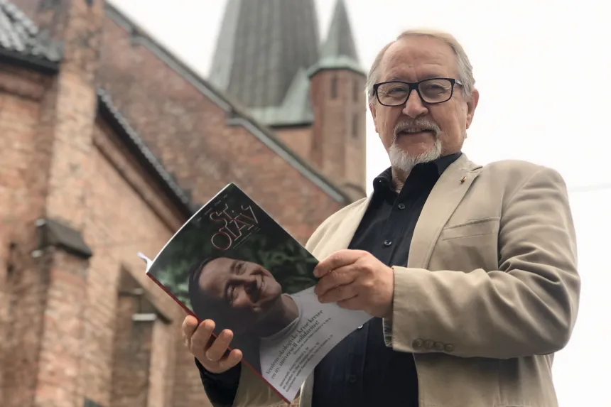 Nils Heyerdahl med en utgave av St Olav tidsskrift i hendene utenfor St. Olav domkirke, Oslo. 