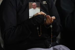 En troende holder en rosenkrans og et fotografi av pave Frans