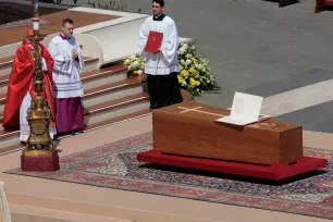 En kardinal og to andre menn står ved pave Frans' kiste på Petersplassen
