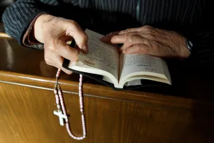 Hender holder en rosenkrans og en bibel med kinesisk skrift